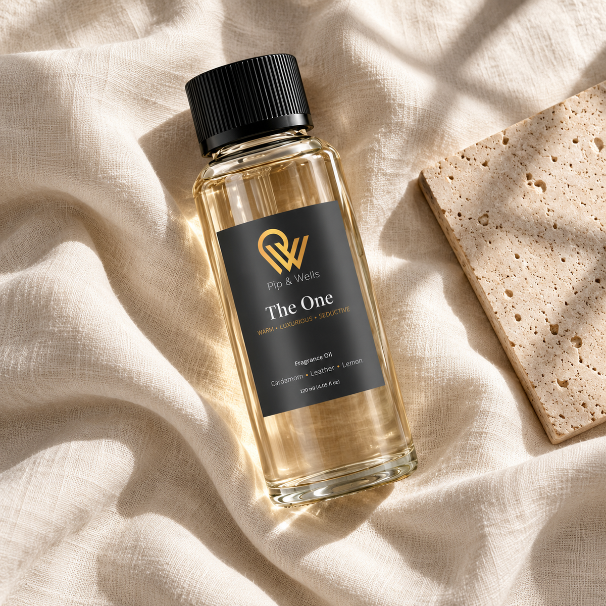 Pip & Wells The One 120 ml fragrance oil bottle on light linen beside a textured stone tile